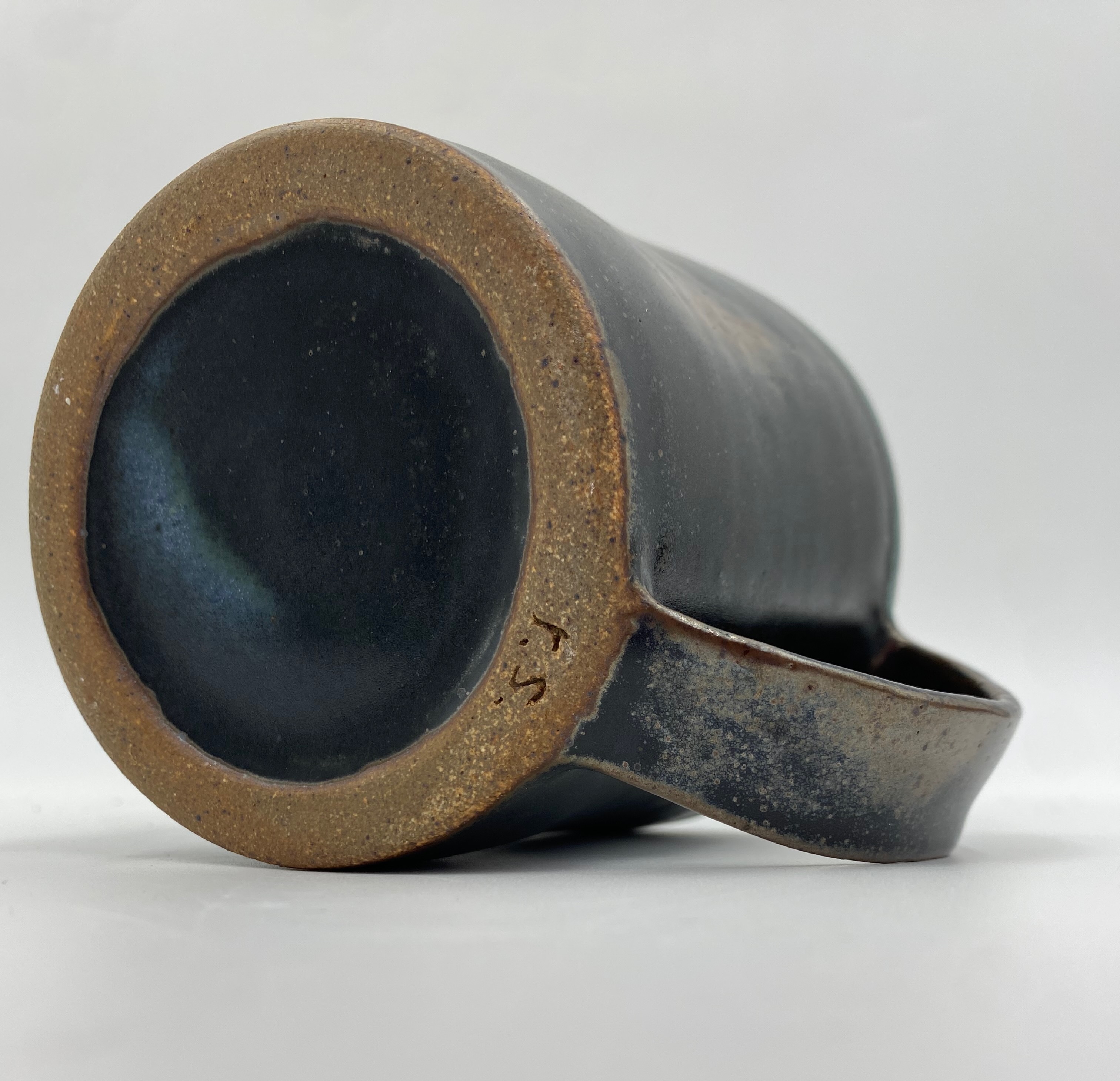 The bottom of a large dark green mug with initials r.s.