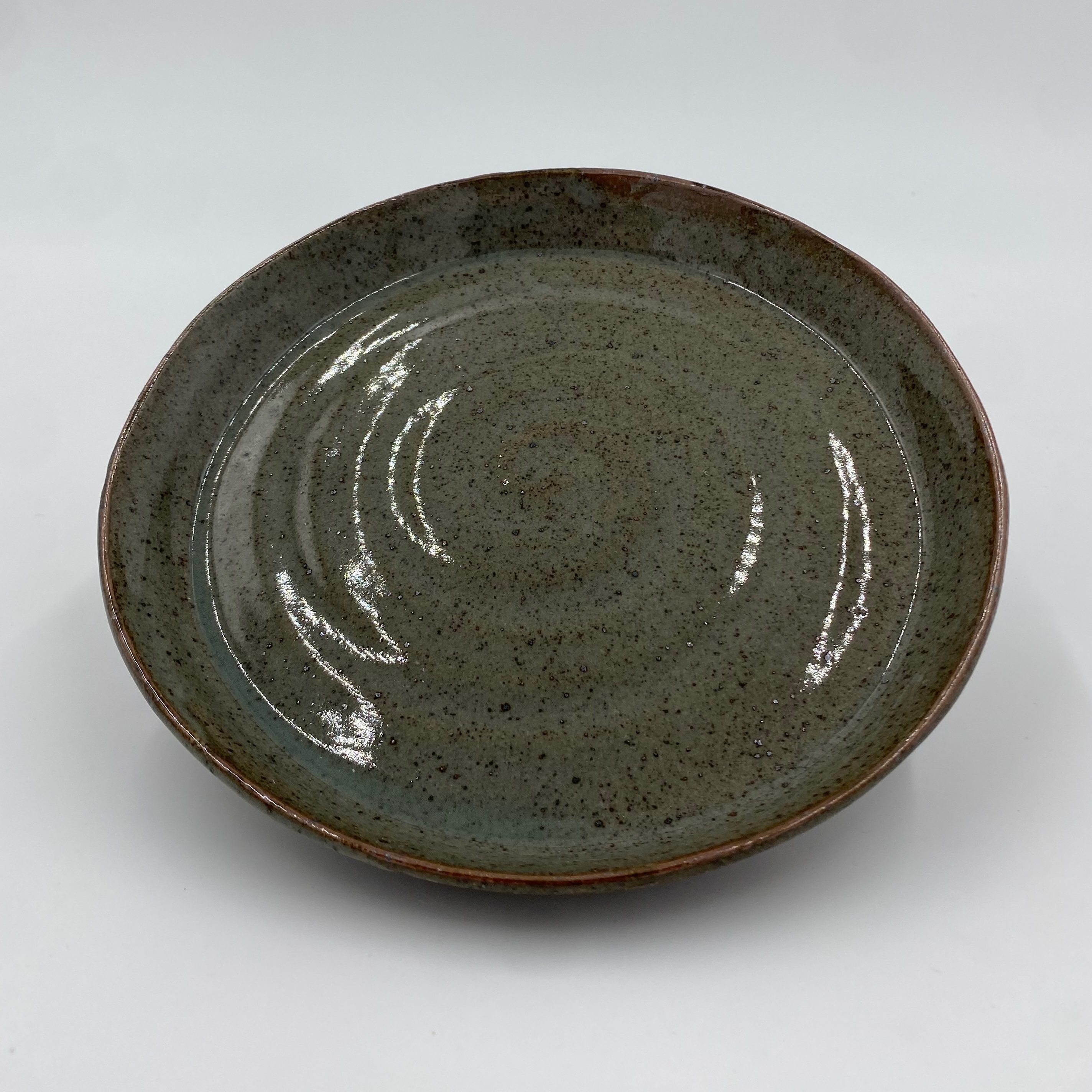 A medium-sized green plate with brown specks and a subtle spiral in the middle.