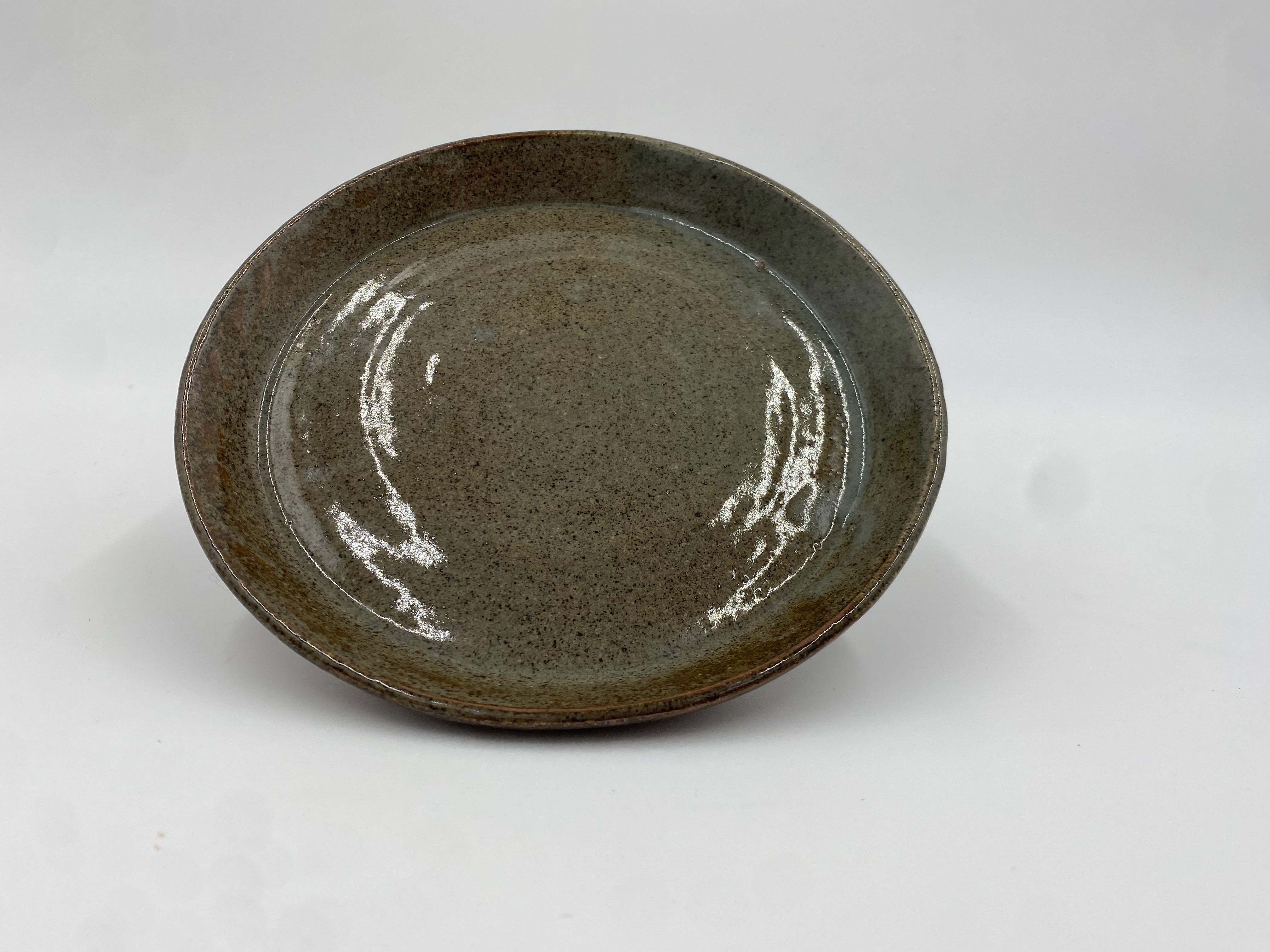 A medium-sized green plate with brown specks and a subtle spiral in the middle.